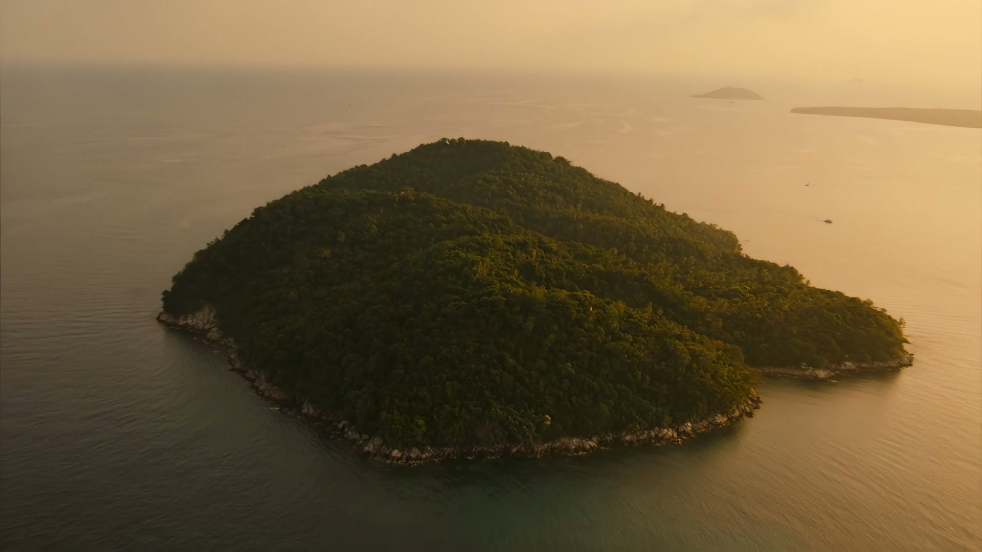 A lush green island in the golden-hour Gulf of Thailand